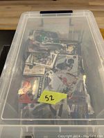 Plastic bin filled with a large collection of sports cards showing the variety and quantity inside.