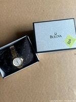 Watch in box with silver Bulova box lid beside it, showing intact packaging and watch on black Bulova pillow