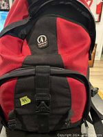 Closed red and black CamRuc branded camera backpack for carrying camera gear.