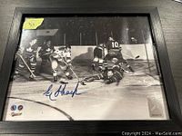 Framed black and white hockey action photo signed by Eddie Shack, showing signature with slight smudge.
