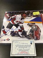 Photo showing Jenna Hefford signed 8x10 hockey action photo with COA and protective sleeve on table
