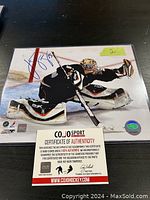 Signed 8x10 photo of JS Giguere with COJO Sport certificate of authenticity placed on top.