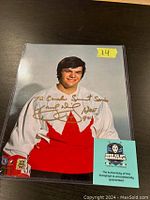 Color signed 8x10 photograph of Marcel Dionne in 1972 Canada Summit Series hockey jersey, with gold autograph and inscription. COA card included.