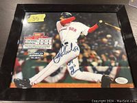 Framed color photo of Orlando Cabrera in Red Sox uniform swinging a bat during a game, signed in blue marker. Includes JSA COA sticker visible on bottom right and scoreboard graphic on left.