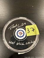 Top view of puck in case showing Patrick Laine signature and inscription with Jets logo in center.