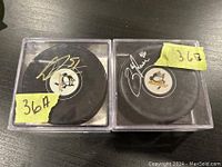 Two hockey pucks with Pittsburgh Penguins logo, each in clear plastic case, signed in silver/white ink, labeled 36A and 36B