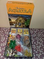Original box open with playing pieces and cards inside, showing compartments with pieces in plastic bags.