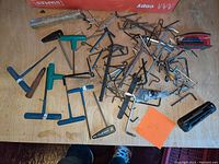 A collection of assorted Allen wrenches and hex keys spread out on a wooden surface.