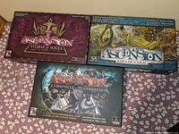 Three boxed Ascension games showing cover art for Chronicle of the Godslayer, Rise of Vigil, and Storm of Souls.