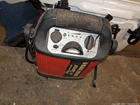 Front view of Black & Decker Start It car jump starter showing control panel, red ribbed body, black handle, and clamps.