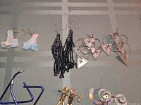 Close-up showing white ribbon bows, long black beaded tassels, and geometric mixed metal hoop earrings with triangle details.