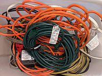 Pile of various colored extension cords tangled together in a container.