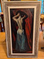 Frontal view of painting in frame displaying figure of woman from behind adjusting hair against dark background with red drapery