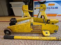 Yellow Rally hydraulic floor jack with long handle pipe placed on the floor.
