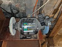 Side view of Ohio Forge bench grinder showing buffing wheel, cylindrically shaped motor housing with labeling, and work light.