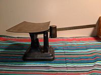 Side view of the black metal base and weighing platform of the vintage balance scale.