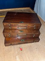 Stack of four vintage wooden drawers with label holders and knobs, showing wear consistent with age.