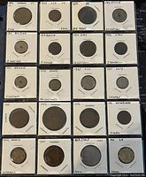 Top view of 20 assorted world coins mounted in cardboard holders with date and country labels visible.