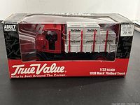 Front view of boxed True Value 1/33 scale 1918 Mack flatbed die cast truck showing red truck and white crates on flatbed.