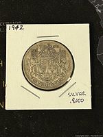 Front side of 1942 Canadian 50 cent silver coin showing crowned shield with lions and maple leaves, inside protective holder.