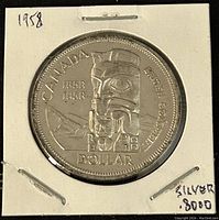 Image of the reverse side of the 1958 Canadian silver 1 dollar coin, showing the totem pole and inscriptions.