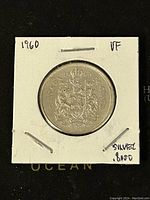 Obverse side of 1960 Canadian 50 cent silver coin showing the royal coat of arms and inscription.