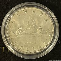 Reverse side of 1962 Canadian silver dollar depicting a canoe with two paddlers, maple leaves, year and inscriptions.