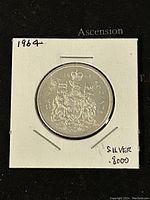 Obverse side of 1964 Canadian 50 cents silver coin showing coat of arms and year.
