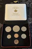 Top view of seven Canadian coins neatly placed in a black velvet case under a white lid showing Royal Canadian Mint logo with maple leaf and bilingual text.