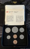 Seven Canadian coins displayed in black case with Royal Canadian Mint informational card.