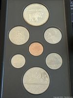 Photo showing the coin set front with eight coins securely mounted in black case, top down view, clear visibility of designs on each coin.
