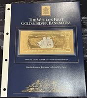 Banknote mounted in a blue display folder titled 'The World's First Gold & Silver Banknotes' with gold emblem and text noting Bartholomew Roberts's Royal Fortune.