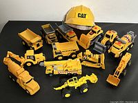 Overview of all 13 pieces showing various types of yellow toy construction vehicles and the CAT helmet.