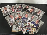 Photo showing a selection of large Donruss Studio hockey cards along with smaller assorted hockey trading cards laid flat on a black surface.