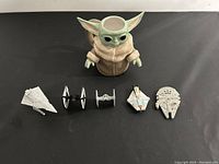Overview photo of Baby Yoda mug and four Star Wars die cast spaceships including Star Destroyer, two TIE Fighters, Y-Wing, and Millennium Falcon on black surface.