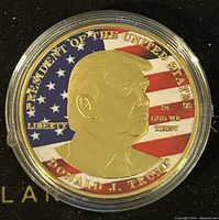 Front photo showing gold tone medallion with colorized USA flag background and profile of Donald J. Trump with inscriptions