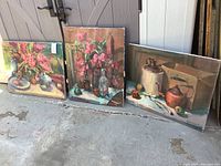 Three Patricia LaGrande paintings on canvas resting outdoors against a wall, showing overall condition and framing.