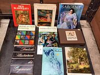 Photo of 10 art books arranged side by side and in stacks, showing titles and covers clearly for identification.