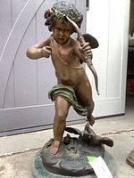 Front angle of bronze cherub statue on circular base, showing bow and arrow and signature