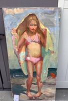 Full view of oil painting on stretched canvas depicting a young girl in pink bikini on beach with towel over her head