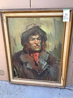 Framed oil painting on canvas depicting a man in a hat and scarf, with a wooden frame that has staining and wear.