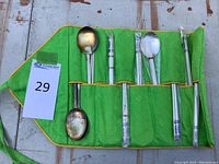 Flat lay of the green case with wrapped utensil sets and two loose spoons outside case