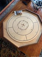 Top side of crokinole board showing wood grain with engraved score rings and plastic bag with playing pieces