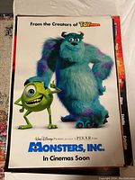 Photo of Monsters, Inc. movie poster side featuring Sulley and Mike characters with promotional text.