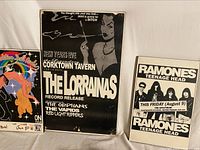 Three concert posters displayed together: colorful Demolition Doll Rods poster, two black and white posters for The Lorrainas and Ramones/Teenage Head
