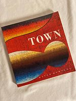 Closed view of the hardcover art book with abstract artwork on cover in red tones.