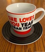 Teacup and saucer displayed on wood table showing front and side view