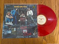 Image showing translucent red vinyl record and matching album cover with band photo and title "Who Are You".