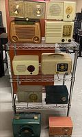 Full view of vintage radios on metal wire shelves showing varied sizes and colors.