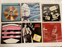 Photo showing six vinyl albums laid out side by side with plastic sleeves. Albums include Elvis Presley, Alan Parsons Project, Split Enz, Swedes From Jazzville, David Bowie, and Ray Bryant.